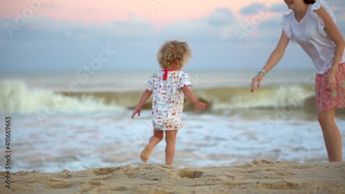 The daughter runs to her mother on the beach. Happy family on the sandy seashore. Beautiful sunrise and sunset. High quality FullHD footage photo