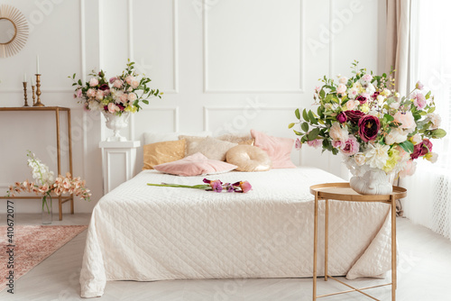 bright lovely bedroom, a bouquet of irises and wild onions on the bed, Beautiful bouquet of colorful flowers in interior of bed room