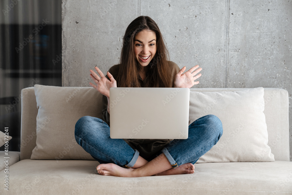 Fototapeta premium Excited brunette nice girl expressing surprise while using laptop