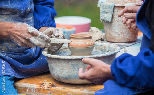 a potter makes a clay pot during a fair, a summer day