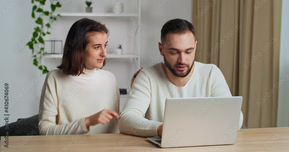 Young caucasian couple spend weekend at home in living room using laptop websurfing searching furniture discuss purchase making order food on-line, enjoy comfort online buying on e-commerce services Young caucasian couple spend weekend at home in living room using laptop websurfing searching furniture discuss purchase making order food on-line, enjoy comfort online buying on e-commerce services