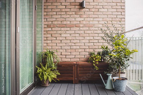 Morden residential balcony garden with bricks wall, wooden bench and plants. photo