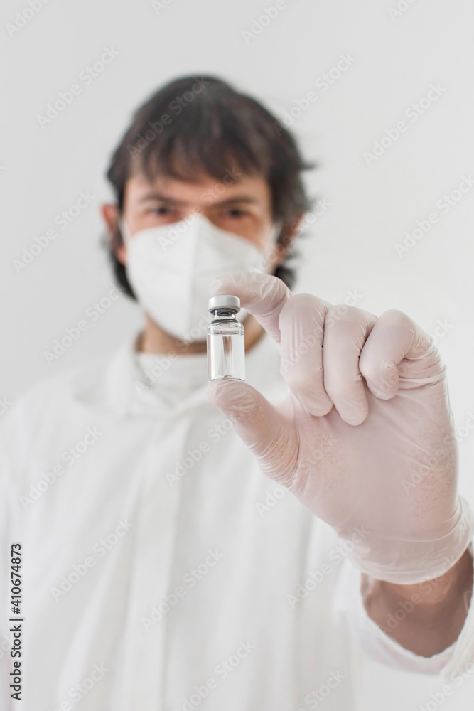 Doctor holding a vaccine bottle and syringe, beginning of worldwide mass vaccination for coronavirus COVID-19, influenza or flu, world immunization concept. Selective focus