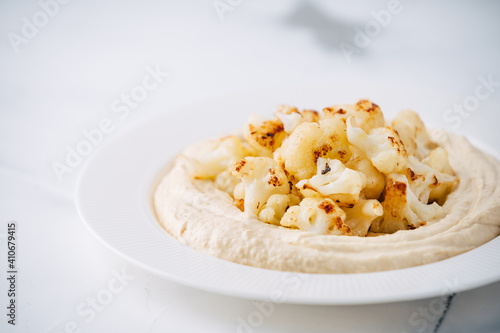 Hummus with fried cauliflower on light concrete background © andrerako