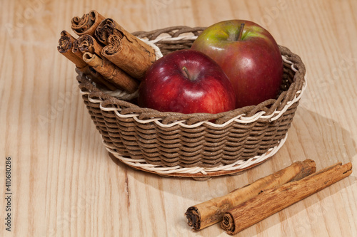 Red apple with a cinnamon stick; photo on wooden background.