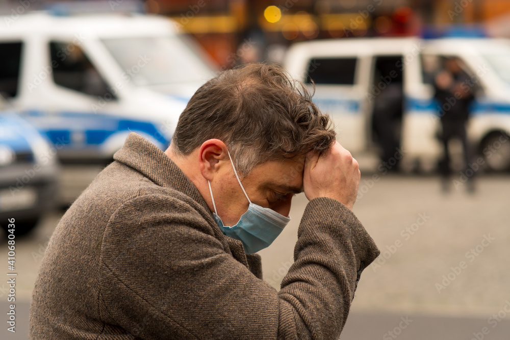 Φωτογραφία A man wearing a medical protective mask with his hands on his head due to receiving bad news or a headache