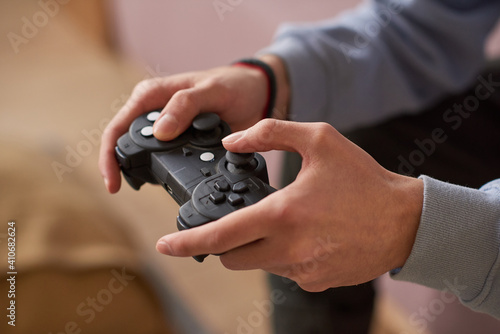 Close-up of young man pushing buttons on joystick while playing video games at home