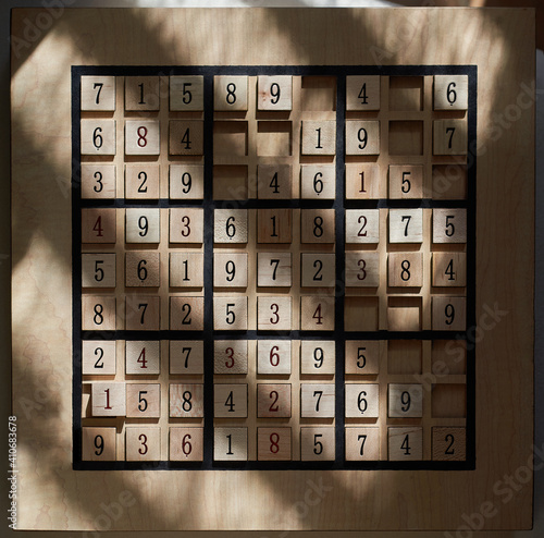 Playing a wood Sudoku game board with puzzle in progress stock photo