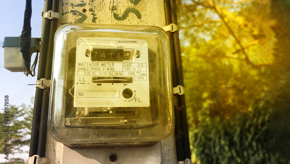A small household electricity meter is hung on a light pole to record the monthly house consumption of electricity. Soft and selective focus.