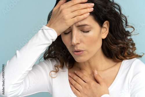 Breathing, respiratory problem, asthma attack, pressure, chest pain, sun stroke, dyspnea concept. Studio portrait of woman received heatstroke in hot summer weather, touching her forehead, isolated photo