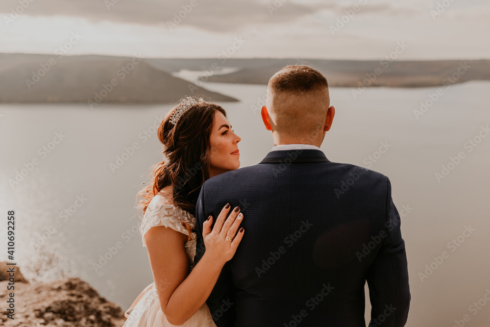 Fototapeta premium loving couple wedding newlyweds in white dress and suit walk in summer on mountain above river