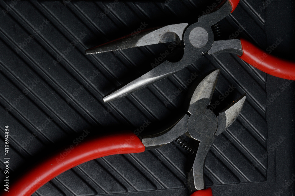 Fototapeta premium The flat nose pliers and pasatige are on the tool box. close-up.