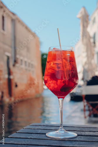 Glass of refreshing Aperol Spritz cocktail served on the deck bar in Venice. Traditional venetian aperitif drink.