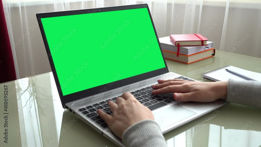 The girl working at home office hands on keyboard. The screen is a green background. The girl working at home office hands on keyboard. The screen is a green background.
