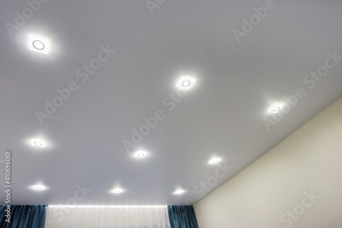 suspended ceiling with halogen spots lamps and drywall construction in empty room in apartment or house. Stretch ceiling white and complex shape. photo