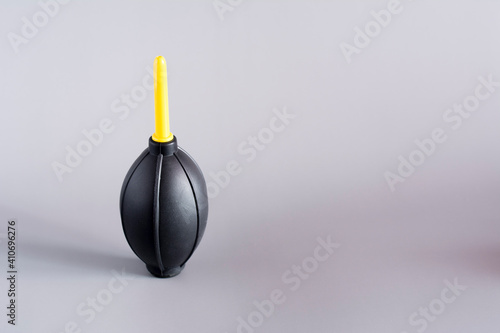 Black air bulb with plastic nozzle blow pipe for photographic equipment on grey background. Black dust blower. Lens cleaner.