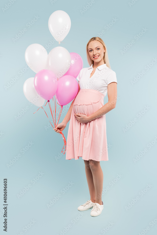 full length of pregnant woman holding balloons on blue full length of pregnant woman holding balloons on blue