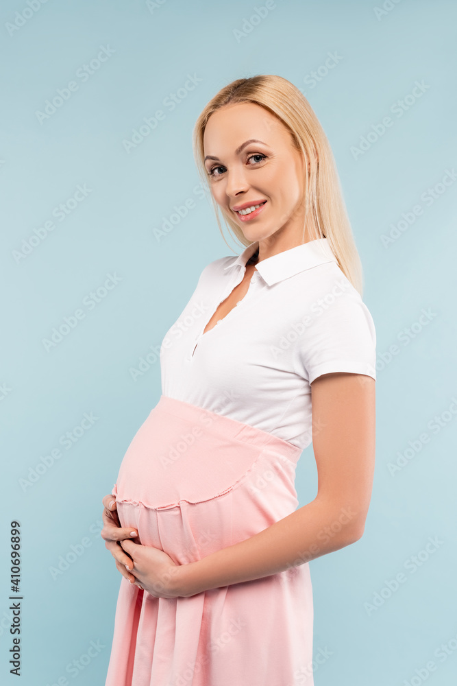 pregnant woman in dress smiling and touching belly isolated on blue pregnant woman in dress smiling and touching belly isolated on blue