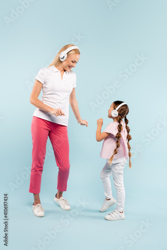 full length of happy mother and kid in wireless headphones dancing on blue © LIGHTFIELD STUDIOS