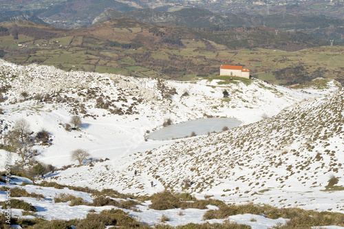 chapel lost in the middle of the mountain surrounded by snowand a frozen lake photo