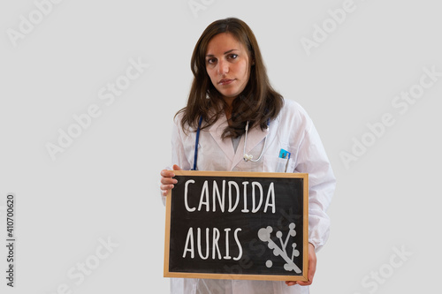 Female doctor holds blackboard with candida auris written on it. Candida auris is the new world pandemic infection. photo