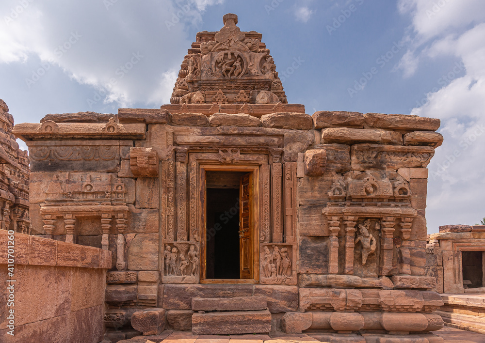 Fototapeta premium Bagalakote, Karnataka, India - November 7, 2013: Pattadakal temple complex. Front side with sculpted doorway of brown stone Jambulingeshwara temple under blue cloudscape.
