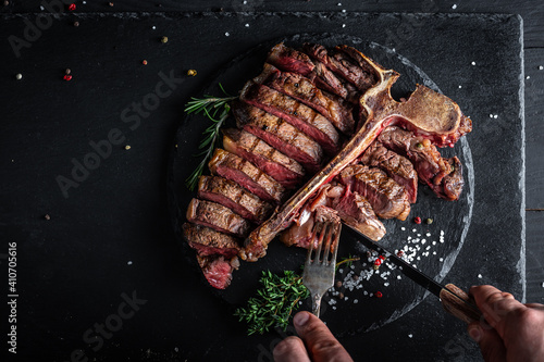 Barbecue aged wagyu porterhouse or T-bone beef steak sliced with large fillet piece with herbs and salt. banner, catering menu recipe place for text, top view