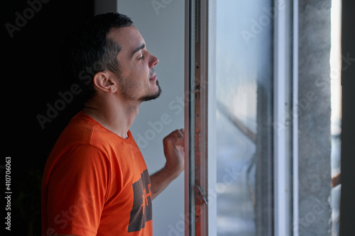 Cold winter weather. man step to window, open it and frosty air rushes from outside through open windows to apartment. Airing housing in cold winter