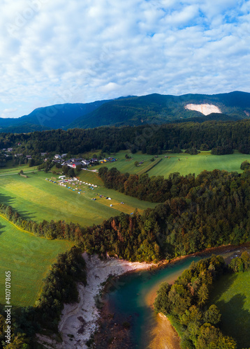 Aerial view. Camping tents on green hill. Garden Park. Mountains and forest. Summer sunny day. Tourism and travel. Misace Slovenia. Vertical photo