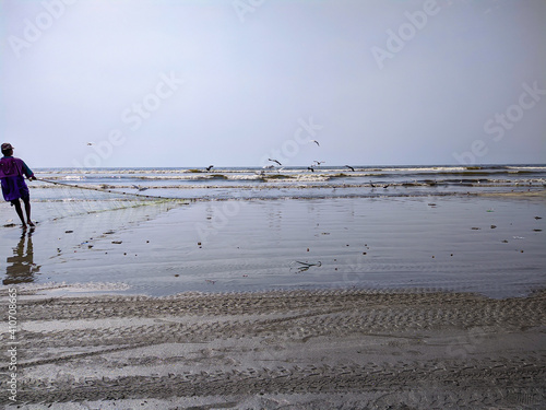 Sea View Clifton Beach Karachi Pakistan On 03-02-2021 A Local Poor Fishermen Trying To Catch Fishes And Sea Herons Trying To Eat His Fishes On His Fishing Nest photo