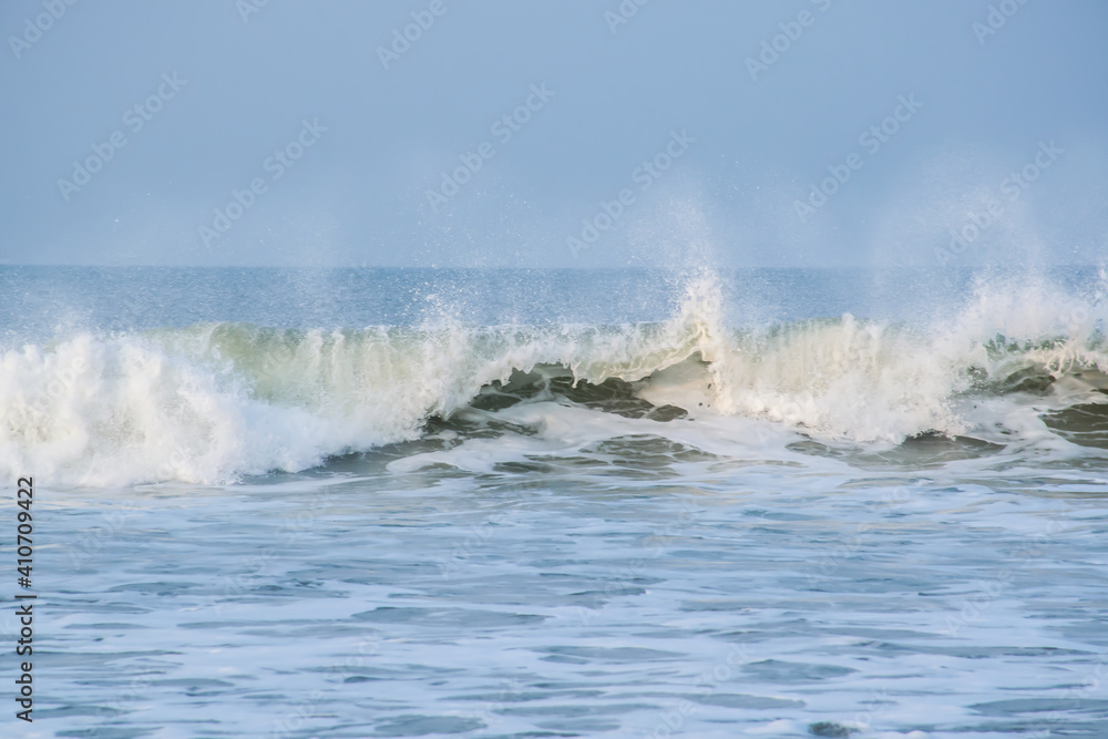 Panoramic landscape view of large foamy sea wave from Arabian Sea splashing with spray of water droplets in the air at Gokarna situated on the West Coast, Karnataka, India.