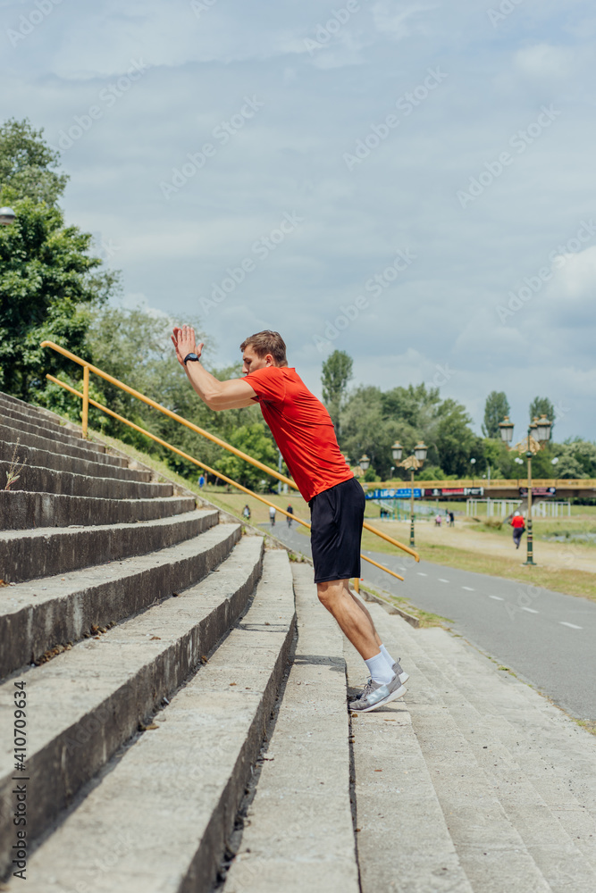 Side view picture of an active male athlete jumping up on stairs in outdoor training. .