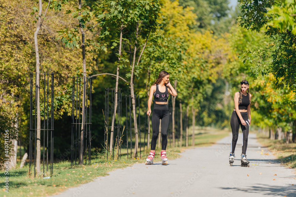 Obraz premium Full-length picture of sexy sportswomen rollerskating in the park