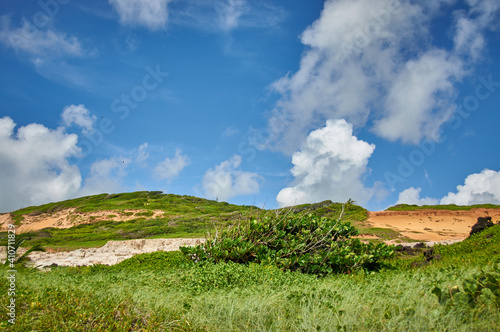 sandy mountains with grass and bushes, blue sky and clouds photo