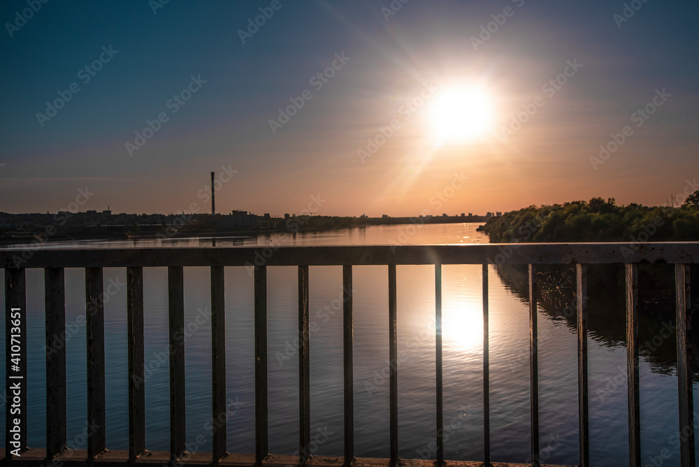 Fototapeta premium View of the Danube river and the city of Belgrade from Pancevo Bridge (Pančevački most) at sunset. Orange sky and clouds in background.