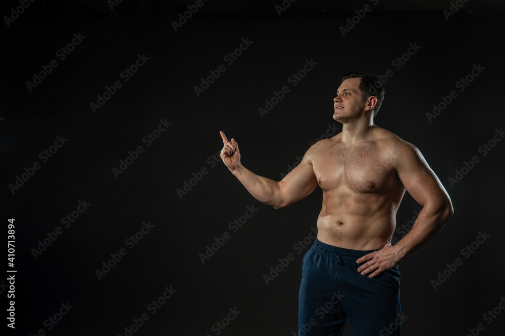 Man's hand points bare torso Young Caucasian male handsome, portrait of an isolated bodybuilder. elegance background black bodybuilder Man's hand points bare torso Young Caucasian male handsome, portrait of an isolated bodybuilder. elegance background black bodybuilder