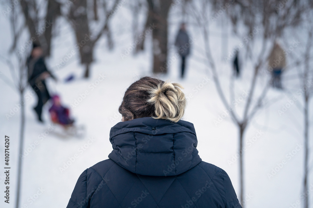 Young woman in snowy park. Back view. Blurred background. Winter landscape. Young woman in snowy park. Back view. Blurred background. Winter landscape.