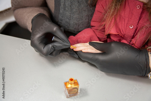 The manicurist paints the child's nails photo