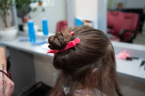 The stylist dyes the child's hair. Hairdresser and little girl in a beauty salon