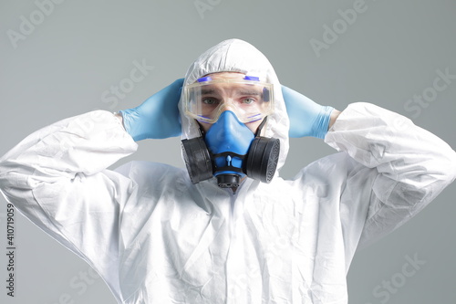 Man in protective suit, goggles, blue rubber gloves and respirator