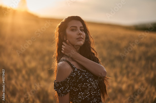 Elegant Woman In A Dress In The Wheat Field at sunset.