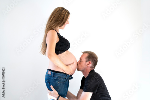 Portrait of young couple the boy kisses the woman's belly feeling love for the birth of their future child