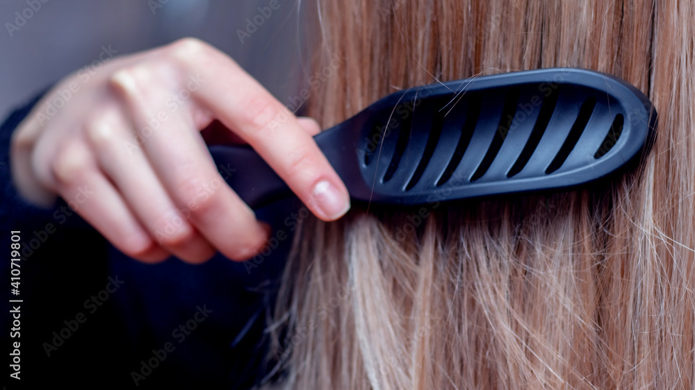 Obraz premium Young girl combs her hair with a hairbrush, hair care