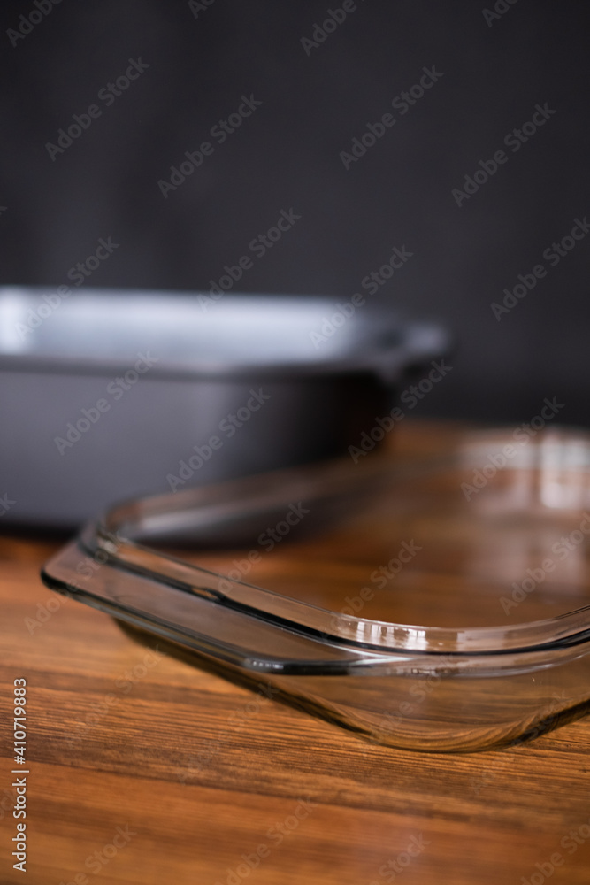 Obraz premium black casserole with a glass cover for baking isolated on wooden background