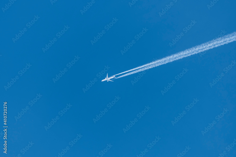 Stunning view of a commercial airplane forming contrails on a blue sky. Stunning view of a commercial airplane forming contrails on a blue sky.