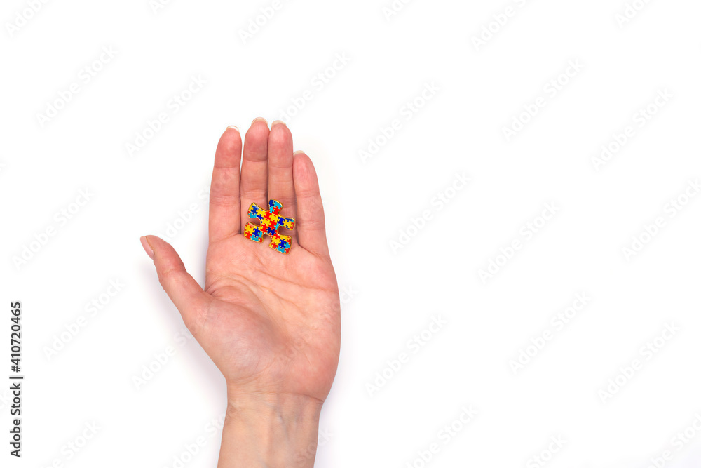 Hand holding autism awareness puzzle. World Autism spectrum disorder Awareness Day, pride, jigsaw. White background. Copy space Hand holding autism awareness puzzle. World Autism spectrum disorder Awareness Day, pride, jigsaw. White background. Copy space