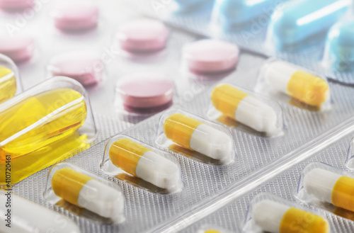 A bunch of medical pills in yellow and other colors. Tablets in plastic packaging.