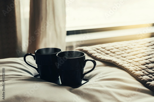 Bed Near Window With Panoramic View And Two Couple Black Cups. Romantic Morning After Wedding Breakfast In Back Light Concept. Hot Drinks Vintage Retro Toned.