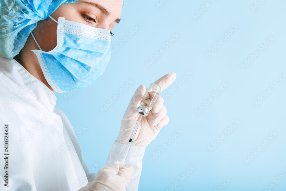 Nurse puts covid 19 vaccine into syringe to give injection. Coronavirus vaccination. Doctor woman make Covid vaccination in medical protective mask and gloves on color blue background with copy space Nurse puts covid 19 vaccine into syringe to give injection. Coronavirus vaccination. Doctor woman make Covid vaccination in medical protective mask and gloves on color blue background with copy space