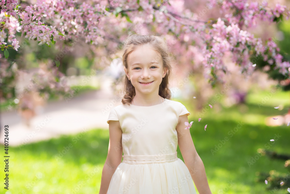 Cute little girl smiles and sniffs flowers in a spring blooming garden, close up Cute little girl smiles and sniffs flowers in a spring blooming garden, close up